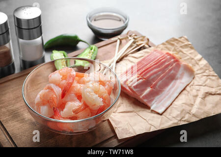 Zusammensetzung mit rohen Garnelen und Speck auf Tabelle Stockfoto