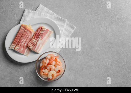 Zusammensetzung mit rohen Garnelen und Speck auf Tabelle Stockfoto