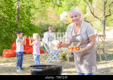 Reife Frau Kochen Gemüse am Grill im Freien Stockfoto