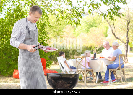 Mann kochen leckere Steaks auf Grill im Freien Stockfoto