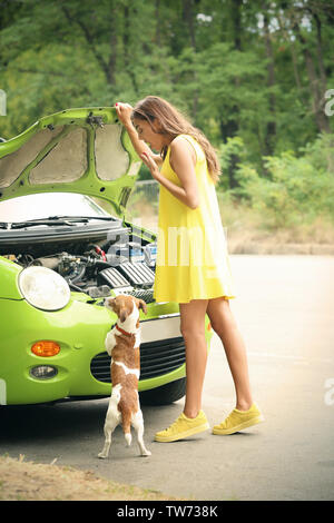 Junge Frau mit Hund in der Nähe von Broken Auto Stockfoto