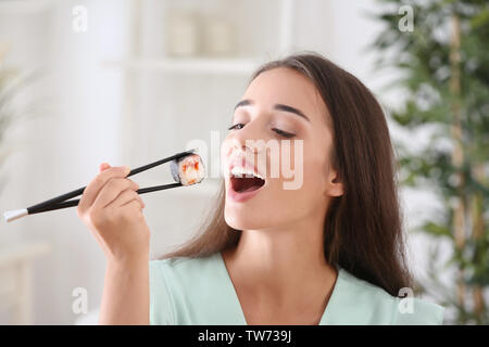 Schöne junge Frau isst Sushi Roll zu Hause Stockfoto