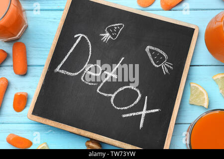 Kleine Schiefertafel mit Wort Detox und Gemüse auf Tisch Stockfoto