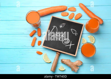 Kleine Schiefertafel mit Wort DETOX, frischer Saft in Gläser und Zutaten auf Tisch Stockfoto