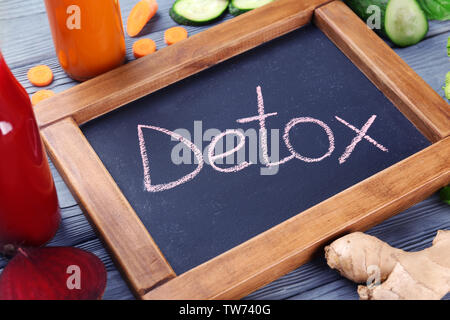 Kleine Schiefertafel mit Wort Detox und Gemüse auf Tisch Stockfoto