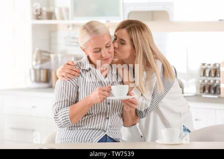 Junge Frau trinkt Tee mit älteren Mutter zu Hause Stockfoto