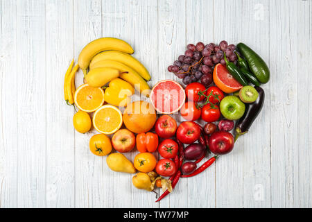 Kreative Zusammensetzung von Obst und Gemüse in Regenbogenfarben auf hölzernen Hintergrund, flach Stockfoto