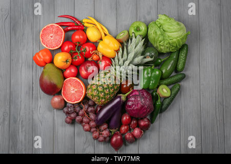 Kreative Zusammensetzung von Obst und Gemüse in Regenbogenfarben auf hölzernen Hintergrund, flach Stockfoto