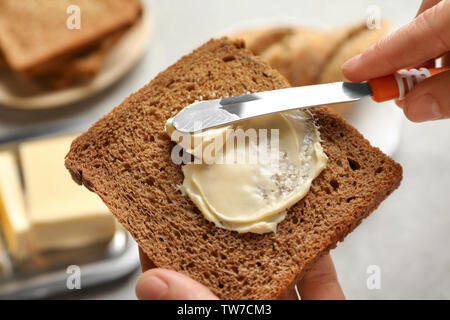 Frau Verbreitung Butter auf Scheibe Brot, Nahaufnahme Stockfoto