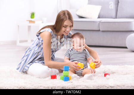 Junge Mutter und niedlichen Baby spielen auf dem Boden zu Hause Stockfoto