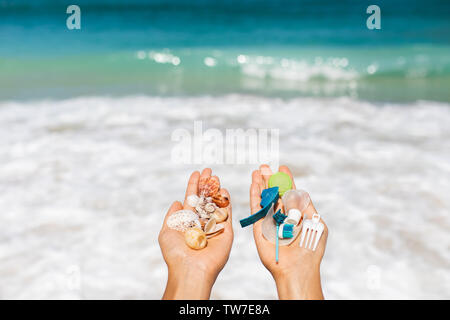 Konzept der Wahl: Natur retten oder weiter aus Kunststoff zu verwenden. Eine Hand, die eine schöne Muscheln, in der Anderen - Kunststoffabfälle. Ozean und tropi Stockfoto