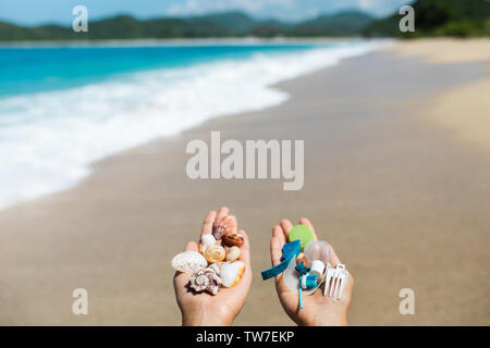 Konzept der Wahl: Natur retten oder weiter aus Kunststoff zu verwenden. Eine Hand, die eine schöne Muscheln, in der Anderen - Kunststoffabfälle. Ozean und tropi Stockfoto