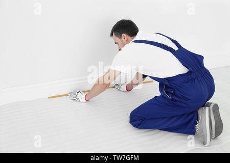 Arbeiter mit Maßband Vorbereitung neuer Teppich zu installieren. Stockfoto