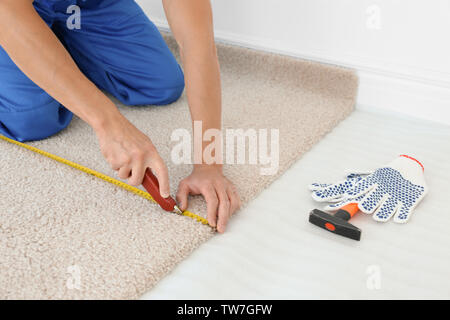 Arbeitnehmer mit dem Fräser während neue Teppichböden installieren im Zimmer Stockfoto