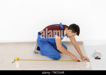 Arbeitnehmer mit dem Fräser während neue Teppichböden installieren im Zimmer Stockfoto