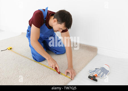 Arbeitnehmer mit dem Fräser während neue Teppichböden installieren im Zimmer Stockfoto