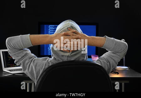 Mann mit Kapuze hacking Server im dunklen Zimmer Stockfoto