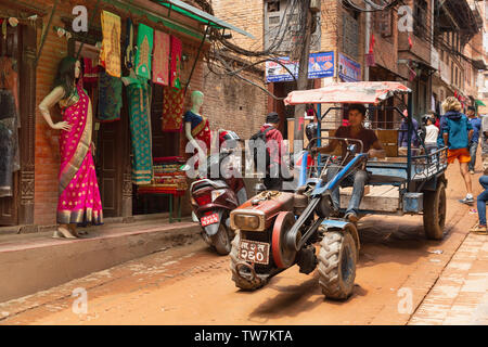 Junge Nepali Mann, der einen Traktor zu einer geschäftigen Stadt Straße, Bhaktapur, Provinz Nr. 3, Nepal, Asien Stockfoto