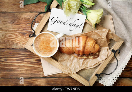 Fach mit leckeren Croissants und Kaffee auf hölzernen Tisch Stockfoto