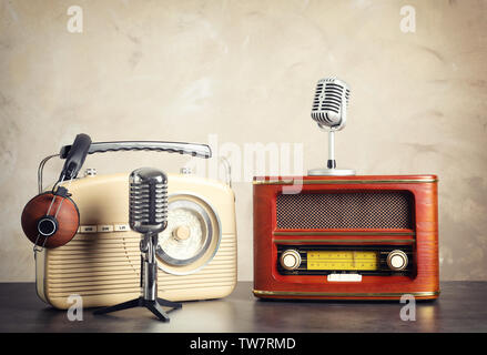 Retro Radios, Kopfhörer und Mikrofone auf dem Tisch an der Wand Stockfoto