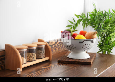 Sieb mit Gemüse und gewürzdosen am Tisch in der Küche Stockfoto