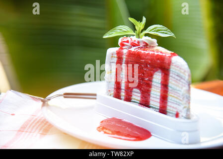 Crape Tortenheber mit Erdbeersauce auf weiße Platte/Stück Kuchen Regenbogen mit Schlagsahne Stockfoto