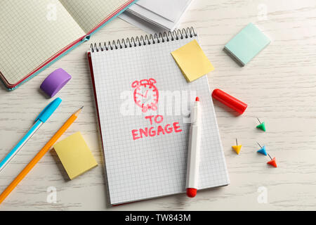 Notebook mit dem Satz ZEIT ZU ENGAGIEREN und Schreibwaren auf weißem Holz- Hintergrund Stockfoto
