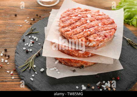 Schiefer Platte mit raw-burger Pastetchen auf Tisch Stockfoto