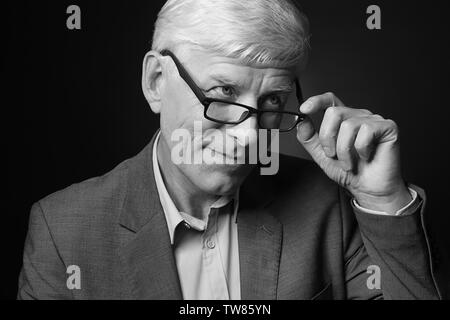 Portrait von Stattlichen reifer Mann in Gläsern auf dunklem Hintergrund Stockfoto