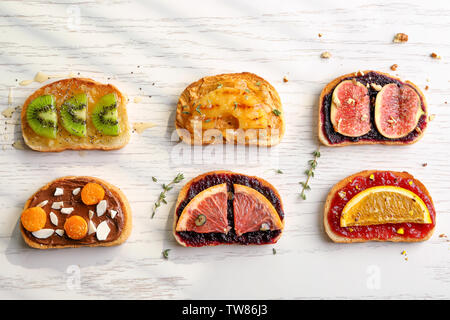Scheiben Brot mit verschiedenen Toppings auf hellen Hintergrund Stockfoto
