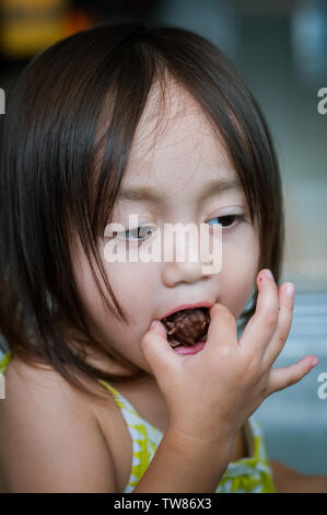 Portrait von asiatischen wenig Kleinkind Mädchen mit vollem Mund von Snacks. Stockfoto