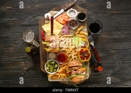 Zusammensetzung mit leckeren double Burger und Gemüse auf hölzernen Tisch Stockfoto