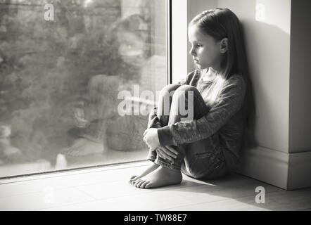 Wenig Trauriges Mädchen in der Nähe der Fenster. Missbrauch von Kindern Konzept Stockfoto