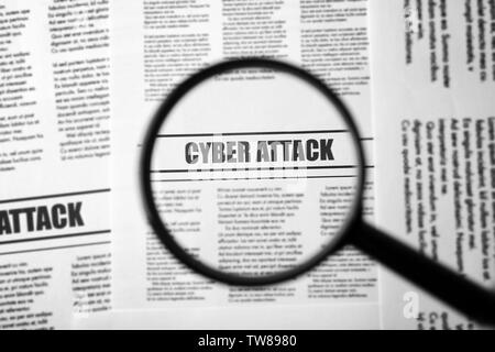 Schlagzeile 'Cyber Attack' in der Zeitung unter der Lupe, Nahaufnahme Stockfoto