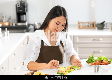 Schöne asiatische Frau Vorbereitung Teller mit Krabben am Tisch in der Küche Stockfoto