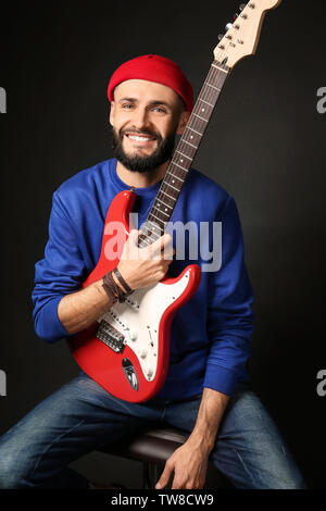 Porträt der jungen gutaussehenden Musiker mit Gitarre auf schwarzem Hintergrund Stockfoto