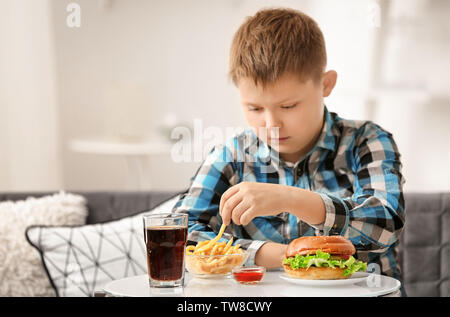 Übergewichtige junge Essen der Trödelnahrung zu Hause Stockfoto