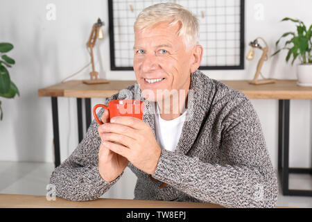 Attraktive reifer Mann Tee trinken im Innenbereich Stockfoto