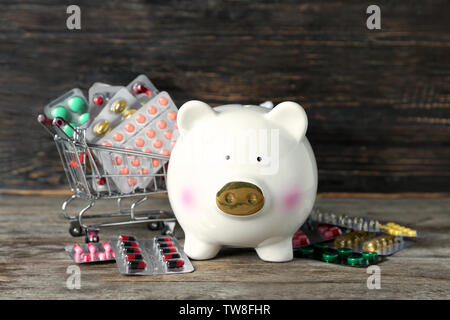 Sparschwein mit Arzneimitteln auf hölzernen Hintergrund Stockfoto