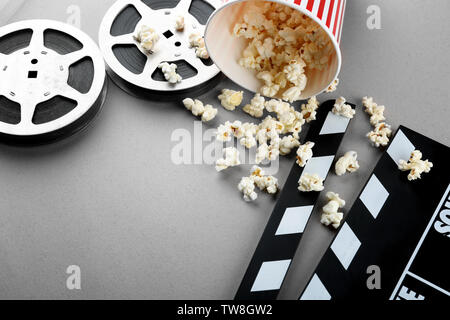 Zusammensetzung mit Popcorn, filmklappe und Kino film auf grauem Hintergrund Stockfoto