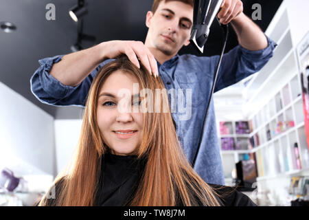 Professionelle Stylisten föhnen Woman's Haar im Salon Stockfoto