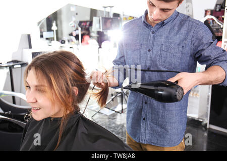 Professionelle Stylisten föhnen Woman's Haar im Salon Stockfoto