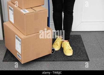 Frau, die in der Nähe der gelieferten Pakete auf der Fußmatte, Nahaufnahme Stockfoto