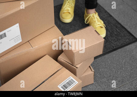 Frau, die in der Nähe der gelieferten Pakete auf der Fußmatte, Nahaufnahme Stockfoto