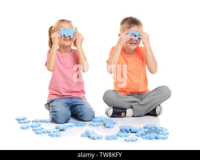 Süße kleine Kinder spielen mit Puzzle auf weißem Hintergrund Stockfoto