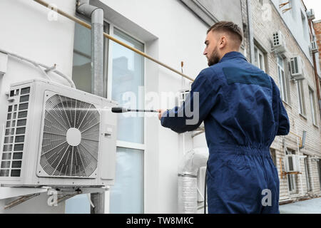 Männliche Techniker Reinigung Klimaanlage im Freien Stockfoto