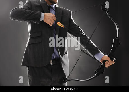 Unternehmer üben Bogenschießen auf dunklem Hintergrund Stockfoto