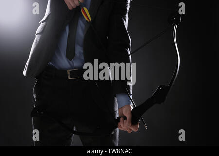 Unternehmer üben Bogenschießen auf dunklem Hintergrund Stockfoto