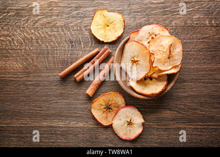 Zusammensetzung mit leckeren Apfel Chips und Zimt auf Holz- Hintergrund Stockfoto