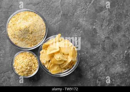 Getrockneten Knoblauch Flocken, Granulat und Pulver in Glasschalen auf grauem Hintergrund Stockfoto